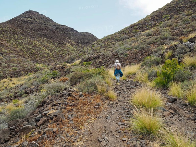 Person hiking on a rocky path through hilly landscape, La Aldea de San Nicolas, Gran Canaria, Spain