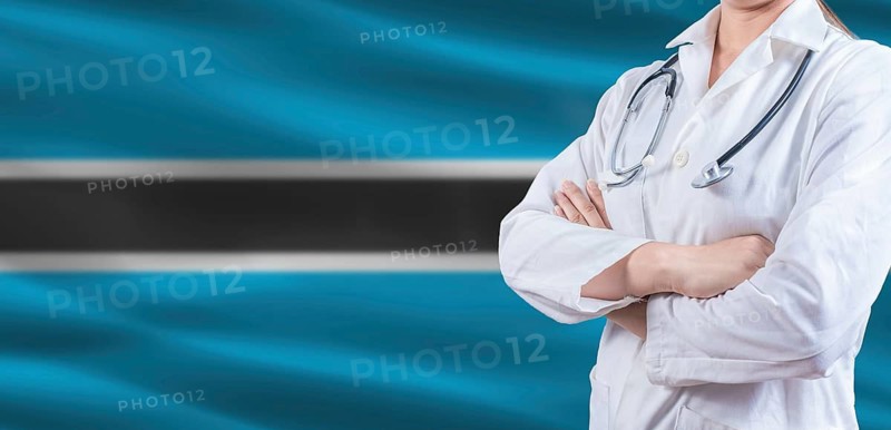 Doctor with crossed arms on Botswana flag. Botswanan health and care concept. Female doctor on Botswana flag