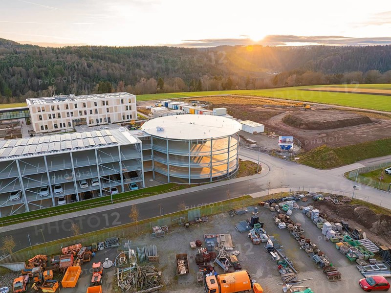 Sunset over an extensive construction site with industrial vehicles, new Calw health campus, Calw district, Black Forest, Germany