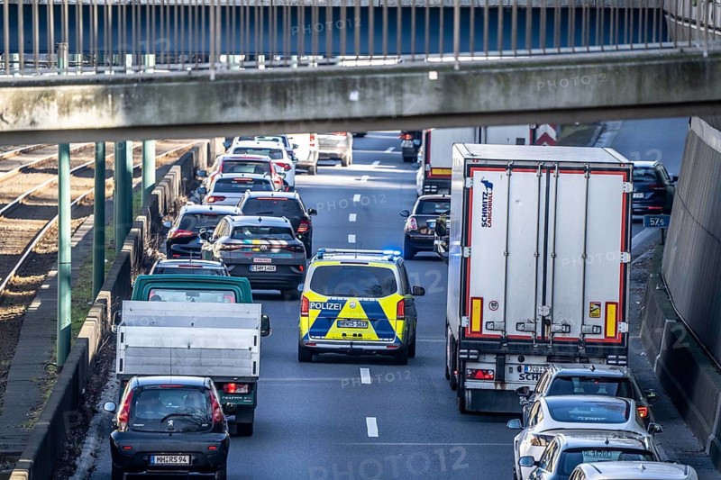 Traffic jam on the A40 motorway, emergency lane, vehicles on the left and right, police patrol car with flashing blue lights and siren, Essen, North Rhine-Westphalia, Germany