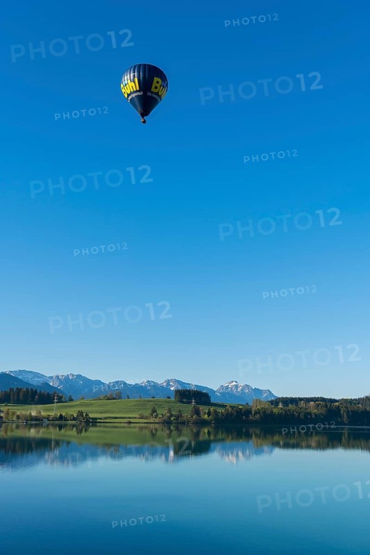 A hot air balloon flies high above a lake with a wide view of the mountains, Lechstausee, Hochplatte with Ammergebirge, Tegelberg, Säuling and Thannheimer Alps, near Urspring, Upper Bavaria, Bavarian Swabia, Bavaria, Germany