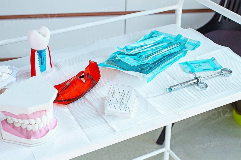 Various instruments, dental models, and hygiene items are laid out on the table in the dental office. natural light