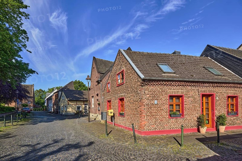 Old town, historic city center, historic brick buildings, street, lantern, mailbox, barrier bollard, roadway, sidewalk, street, paving stones, trees, blue sky, cirrus clouds, Burgweg and Neustraße confluence in Mühlenstraße, Wachtendonk, Kleve district, North Rhine-Westphalia, Germany