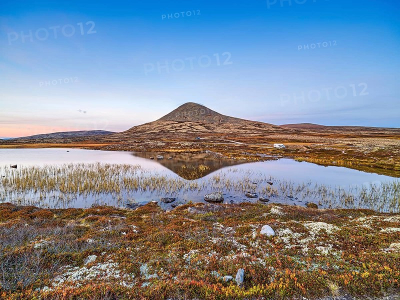 A calm mountain lake with a clear reflection at dusk, surrounded by nature, Rondane National Park, Norway