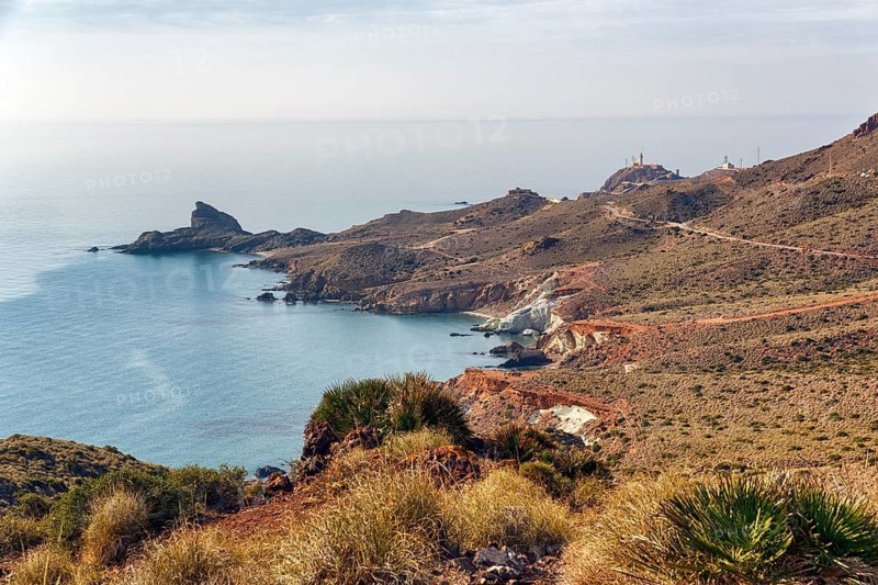 Morrón de Punta Baja coastline, volcanic mountains and bays, volcanic rocks, wild coastal landscape, Faro de Cabo de Gata lighthouse on the horizon, Collado de la Vela Blanca viewpoint, Cabo de Gata-Nijar nature park Park, Almeria, Andalusia, Spain