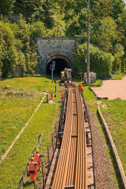 Workers carry rails near a railway tunnel surrounded by green vegetation, electrification of the Hochrheinbahn, conversion of the railway station, Waldshut, Tiengen, Germany