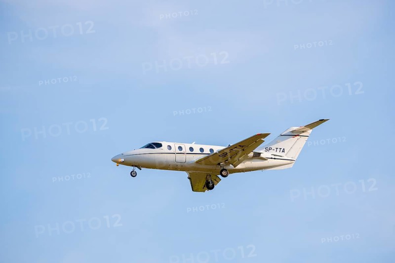 A white private jet flying through the blue sky, clearly visible, light jet, Hawker 400 XP