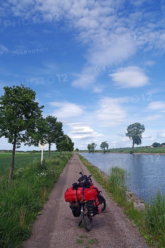 Relaxing bike trip along a narrow path next to a canal under a clear sky, Götaleden, Göta Canal, Töreboda, Sweden