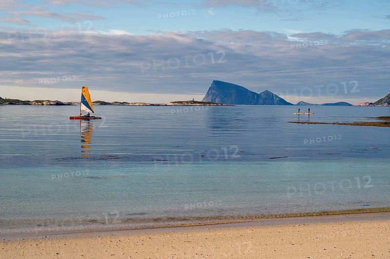 A quiet beach, a small sailboat and islands on the horizon under a cloudy sky, calendar picture, Sommaroy, Sommarøy, Troms, Norway