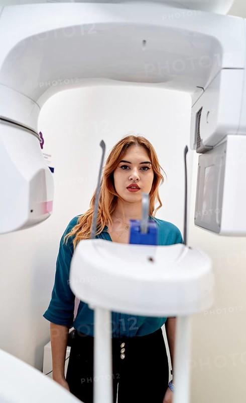 A patient stands ready for a dental X-ray in a modern clinic. The advanced equipment highlights the importance of technology in dental diagnostics and patient care
