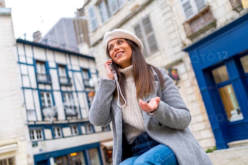 Woman with french style clothes talking to the mobile sitting in the street