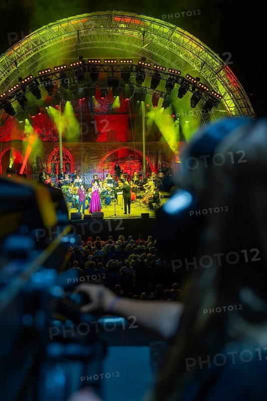 Visitors watch a concert under imaginative lighting with a cameraman in the foreground, Klostersommer, Calw Hirsau, Black Forest, Germany