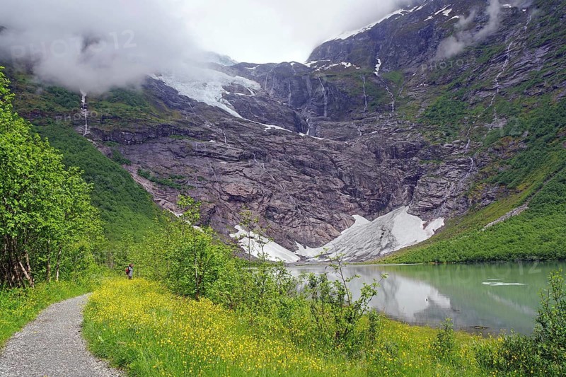 A narrow path leads to a majestic mountain with a waterfall in foggy surroundings, glaciers, climate change, boyabreen, Fjaerland, Norway