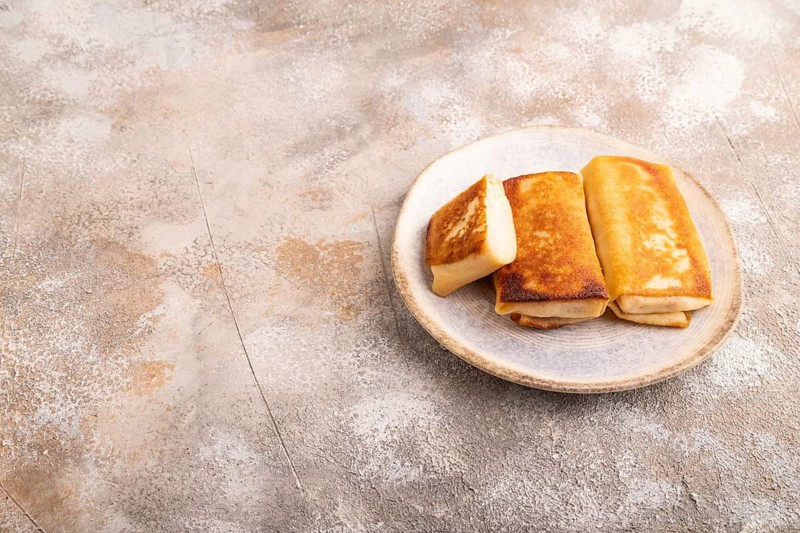 Fried crispy pancakes with meat and cheese on brown concrete background. side view, copy space