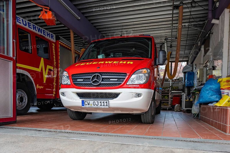 Red fire engine in a garage. The floor is tiled, the door is open, Gechingen fire department, Calw district, Germany