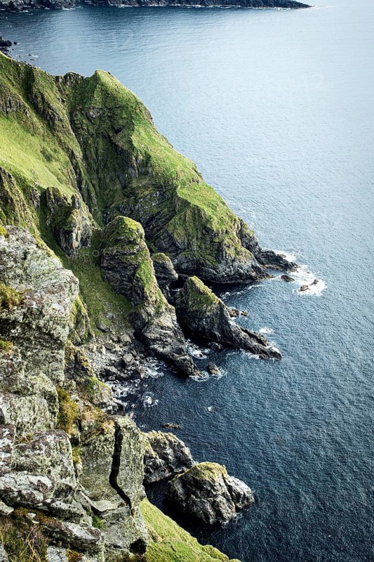 Green, rugged cliffs fall steeply into the blue sea, slightly cloudy sky, bird protection island, Runde island in Norway