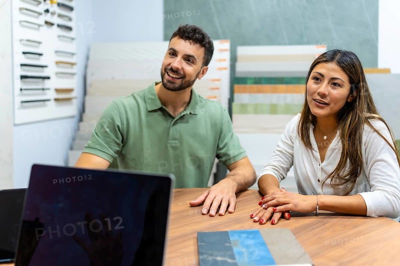 Young couple discussing renovation ideas and choosing materials with an expert at a home improvement store, actively planning their new interior design project