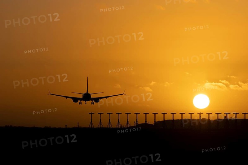 Boeing 737 commercial passenger airliner jet aircraft of Ryanair airways in flight on approach to land over runway lights at sunset at London Stansted airport, Essex, England, United Kingdom