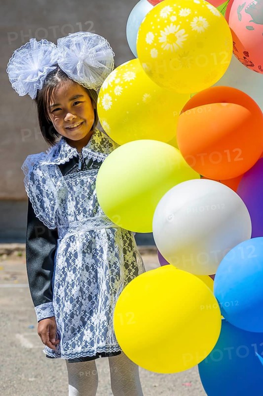 Happy schoolgirl with colourful balloons on the first day of school, Issyk-Kul region, Kyrgyzstan