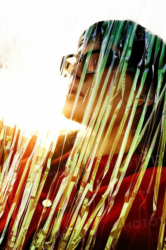 A uniquely artistic portrait of an ethnic Middle Eastern woman, captured behind shimmering strands. Rays of sunlight illuminate her face, creating a dramatic effect