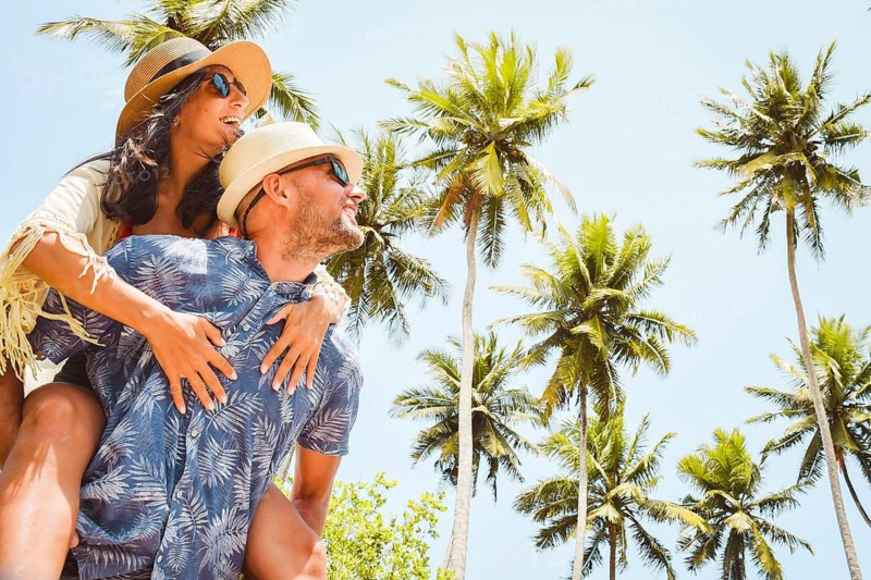 Love Couple Relaxing on the Beach under palm trees