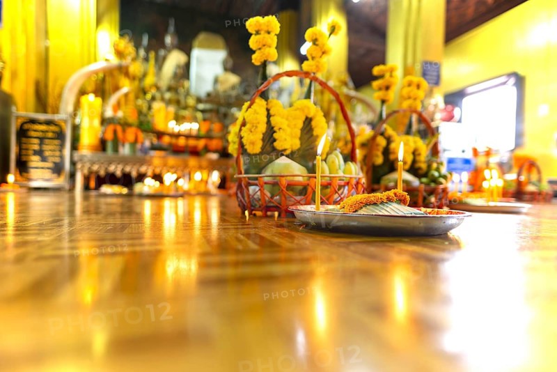 Sacrifices with candles, in front of numerous Buddhas and the City Pillar, which is considered the home of the city's protective spirit, Wat Si Muang temple complex, Vientiane, Laos