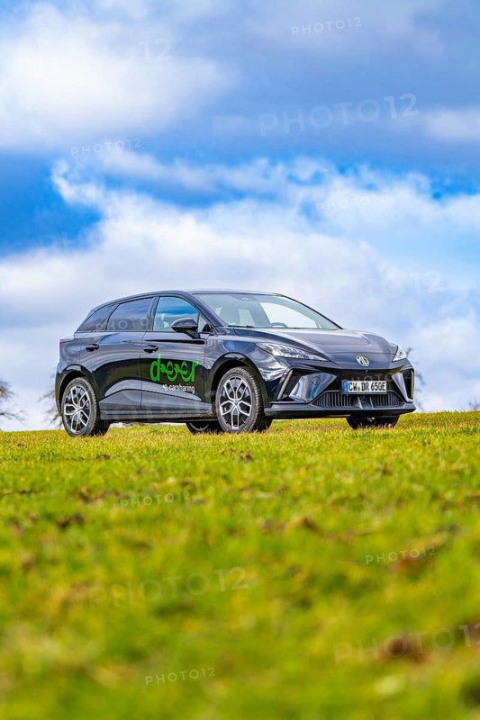 Black car parked in a meadow, blue and white sky in the background, e-car sharing, Deer Mobility, MG4, Calw, Germany