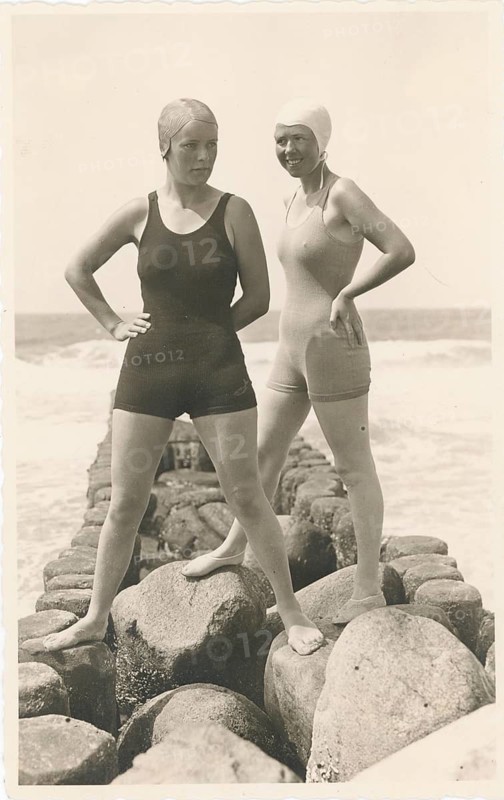 Westerland, Sylt, Baden, swimwear, leisure, summer, Two woman in bathing suits and swimming caps pose on a stone wall by the sea, around 1930