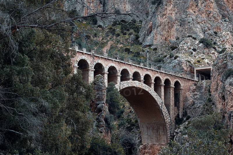 Historic viaduct in a rocky, wooded landscape on the Caminito del Rey path, Malaga, Spain