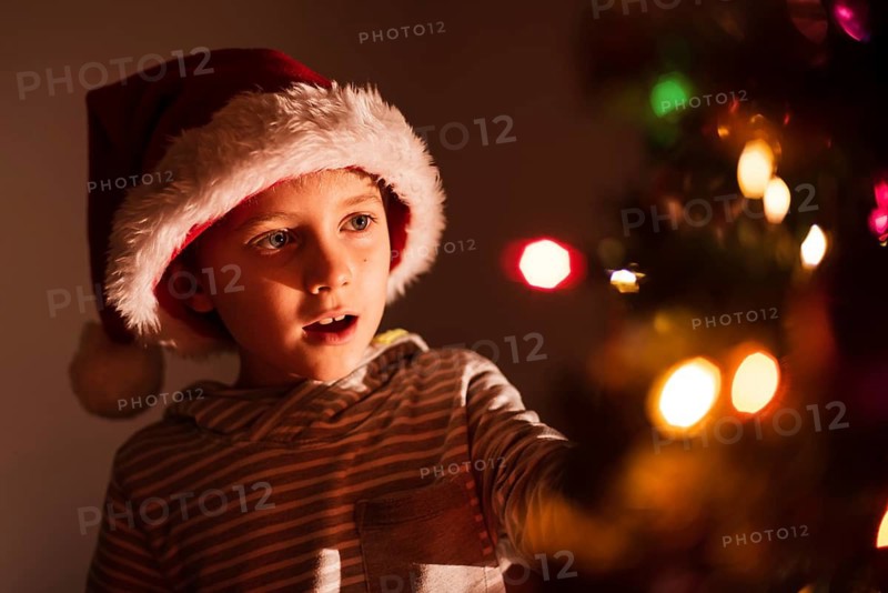 Portrait of 8 years old boy decorating Christmas tree