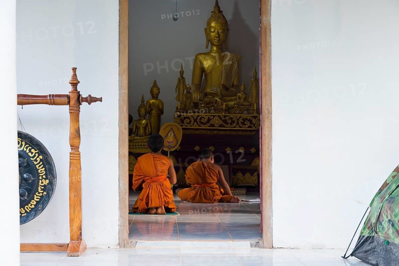 Laotian novices in orange robes in front of a golden Buddha figure in a newly built Buddhist monastery in the village of Muang Ngoi on the Nam Ou River, Phongsali province. laos