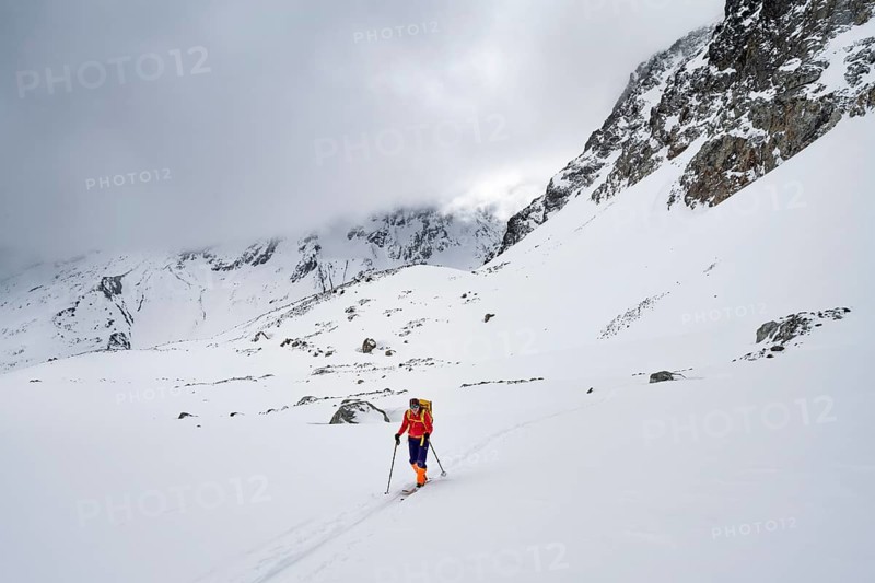 Ski tourer in wintry mountain landscape with cloudy mountain peaks, ascent to Piz Laviner, Grisons Haute Route, Albula Alps, Rhaetian Alps, Grisons, Eastern Switzerland, Switzerland