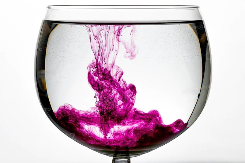 Purple colour unfolds artfully in a glass of water and produces a creative play of colours