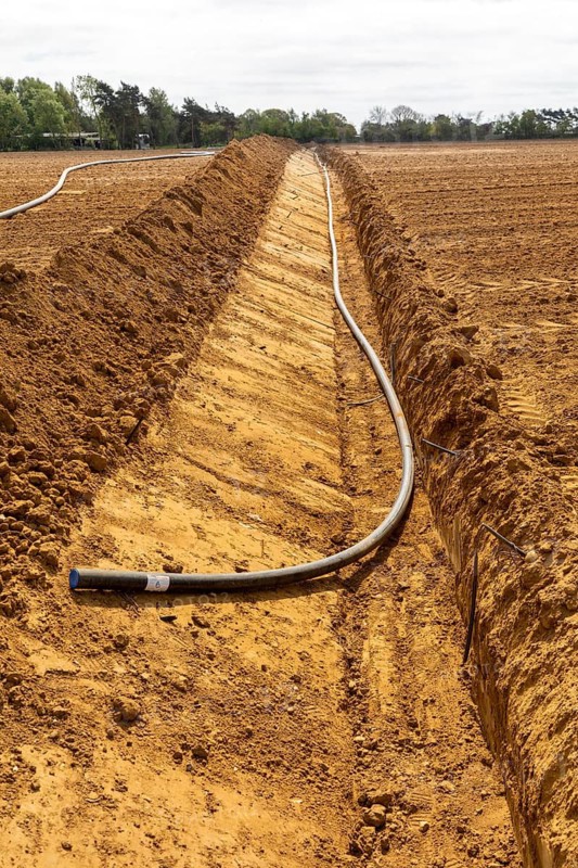 Poly pipe subsurface irrigation system in excavated ditch across sandy field, Shottosham, Suffolk, England, UK