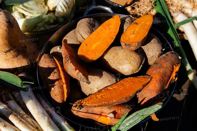 Close-up of fresh calsots and sliced sweet potatoes ready for a traditional Catalan calsotada. Embrace local flavors and culinary heritage with this delightful outdoor dish