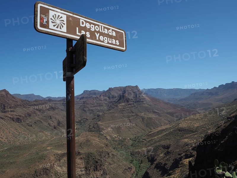 Signpost in the foreground in a dry mountain landscape with clear blue sky, Barranco de Fataga, Gran Canaria, Spain