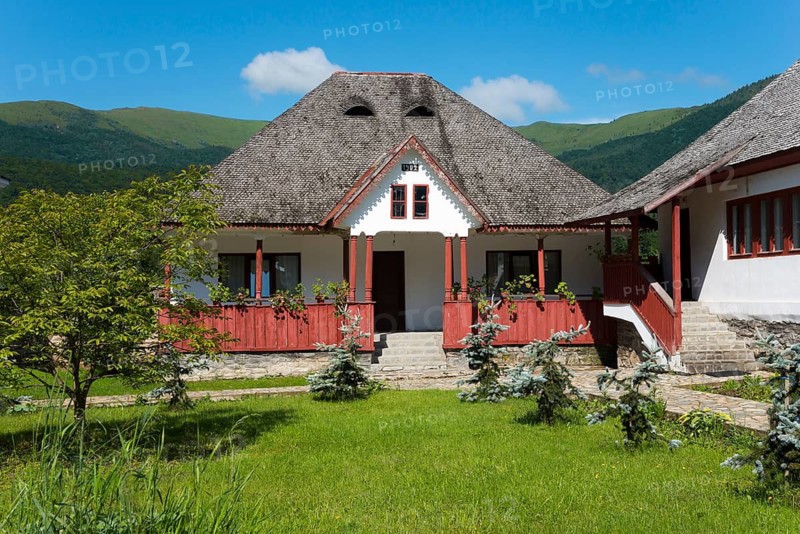 Traditional house with shingle roof and red fence in front of picturesque mountains, Romanian Orthodox Monastery Cheia, Maneciu, Maneciu, Prahova, Wallachia, Romania