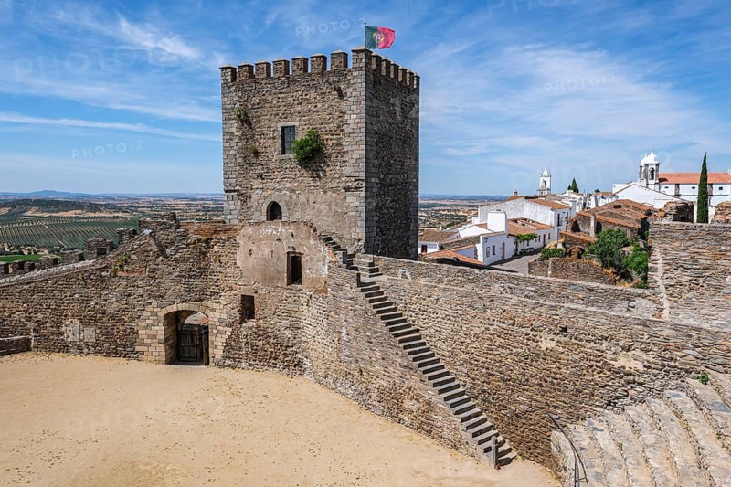 Castle complex with tower, stairs and view of a historic city under clear skies, Monsaraz, Évora, Portugal