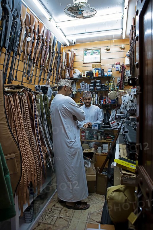 Omani men in dishdasha in the gun shop in the souk or soug or market, old town, Nizwa, ad-Dachiliyya region, Oman