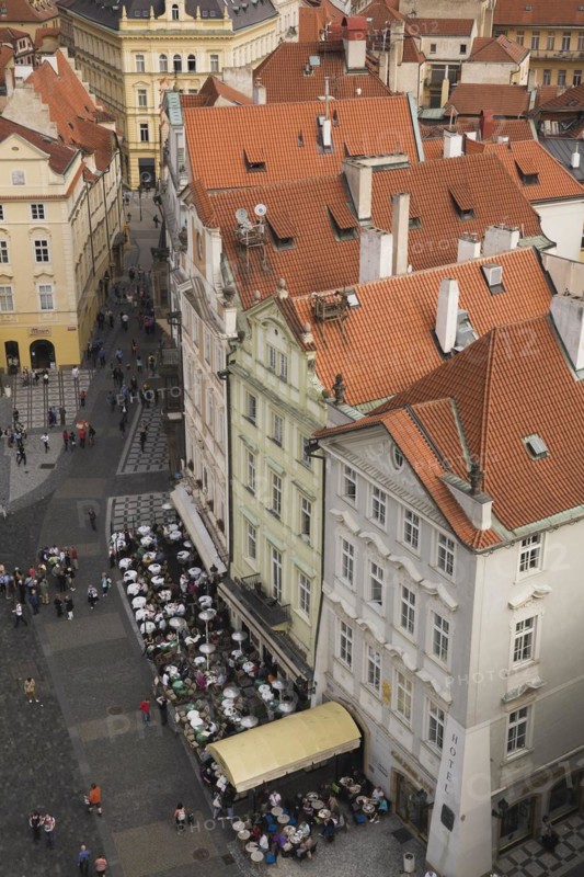 High angle view of buildings with traditional terracotta ceramic tiled rooftops and restaurant terrace with tourists, Old Town Square, Prague, Czech Republic
