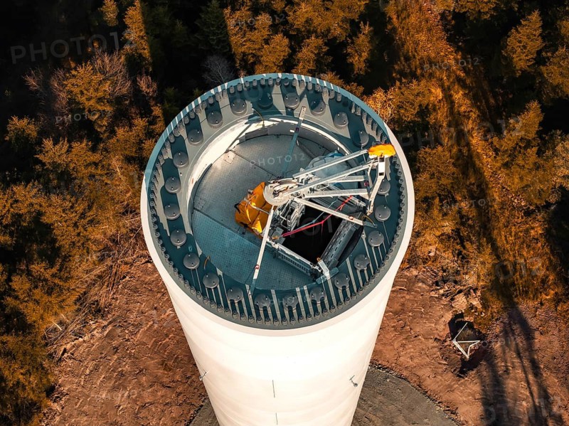 A wind turbine in a wooded area seen from above, surrounded by autumnal trees, wind turbine construction, Calmbach, Black Forest, Germany