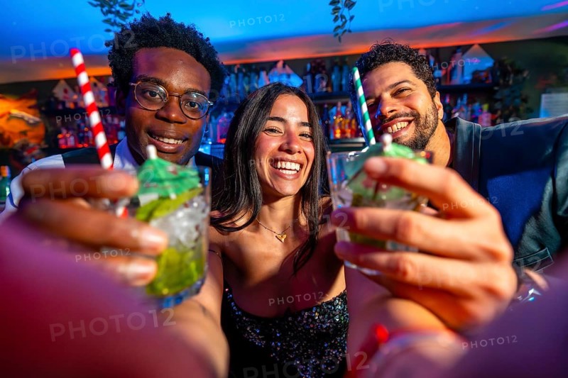 Cheerful multi ethnic friends enjoying cocktails at a vibrant bar, celebrating the weekend nightlife