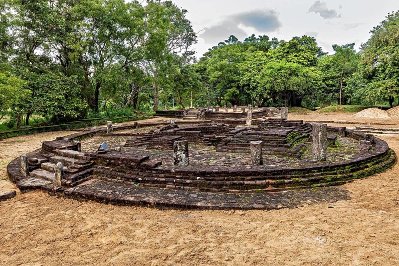 Circular stone complex with remains of columns, surrounded by greenery, temple ruins near Sigiriya in Sri Lanka