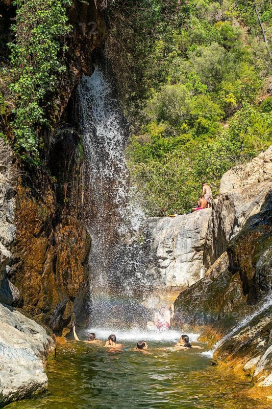 Men and woman bathing in the natural rock pools and waterfalls of Charco del Canalon, Rio Verde river, Istan, Sierra de las Nieves National Park, Andalusia, Spain