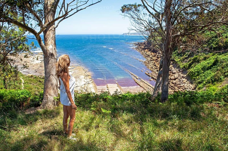 Middle aged woman looking at the landscape in Liñera point cove in western Cantabria, a region of northern Spain in the Cantabric sea