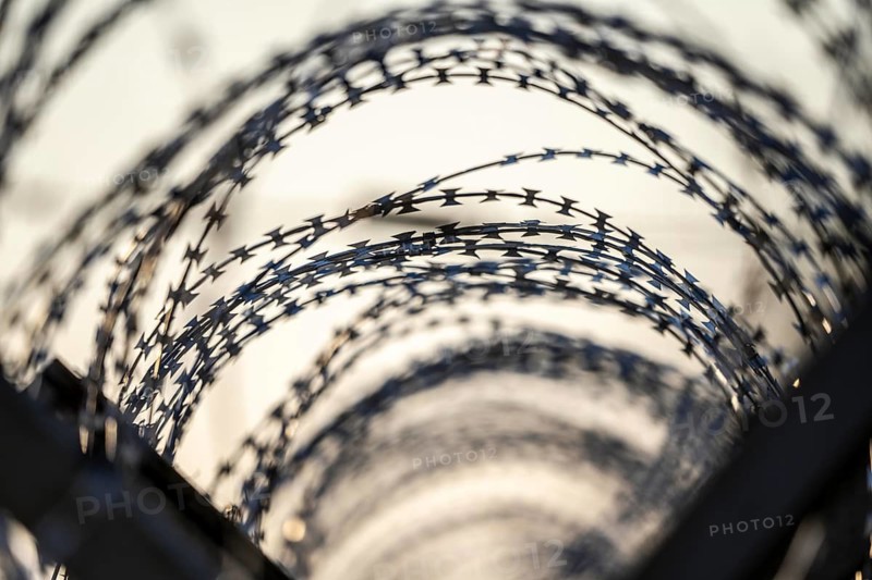 Symbolic image security, S-wire rolls, NATO wire, on a fence top, demarcation of a property, prevention of unauthorised access, strip steel wire with sharp blades
