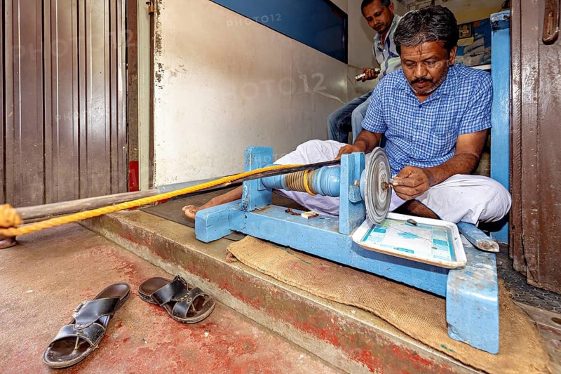 Man in blue shirt working with a sharpener sitting in a small room, The gemstone cutters in the city of Ratnapura in Sri Lanka