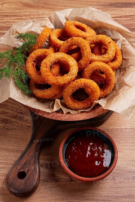 Deep fried onion rings, appetizer, with tomato sauce, on a wooden table, no people, favorite dish