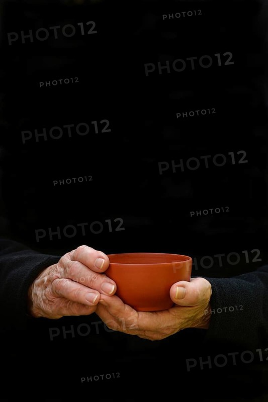 Hand holding clay tea bowl, dark background