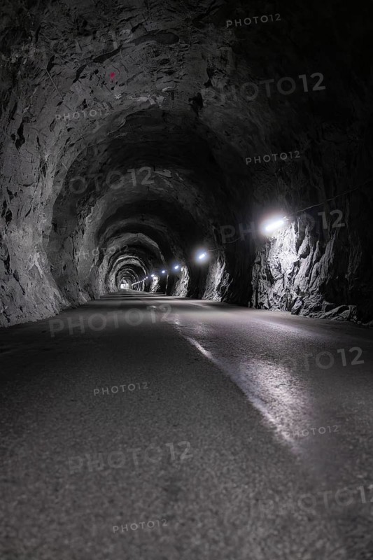 Interior view of an illuminated tunnel with rock faces and asphalt road, Zillertal, Austria, Germany
